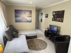 un soggiorno con un divano e una TV di Secure cottage with Wifi and PLEX OR Tambo Airport a Germiston