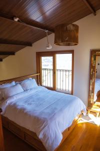 a bedroom with a large bed and a window at Chalé Vale Paraíso in Paraisópolis