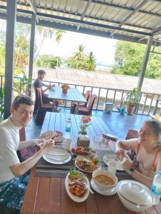 a group of people sitting at a table eating food at The white resort & restaurant koh yao yai in Ban Khlong Hia