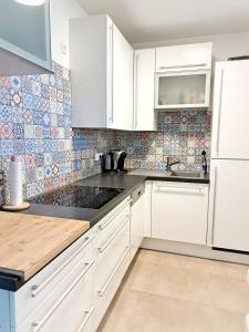 eine Küche mit weißen Schränken und Wandfliesen in der Unterkunft Hanslgasse Private Rooms in Wien