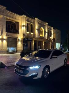 a white car parked in front of a building at night at Old Saroy Hotel in Samarkand