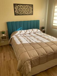 Una cama grande con cabecera azul en un dormitorio. en Complejo Médanos II, en San Bernardo