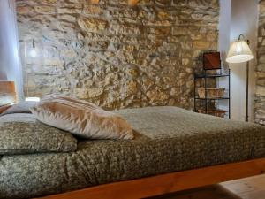 a bed in a room with a stone wall at Casa Rural Haiku in Bojar