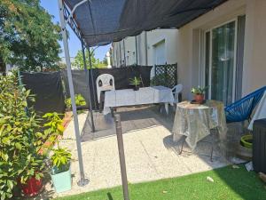 a patio with a table and chairs and an umbrella at Maison au calme a Arnage in Arnage
