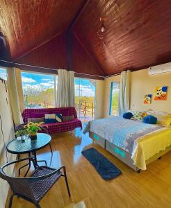 a bedroom with a bed and a couch and a table at Chalé Sun Happy in Serra de São Bento