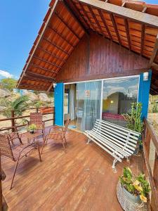 a porch with a white bench on a wooden deck at Chalé Sun Happy in Serra de São Bento +29 photos