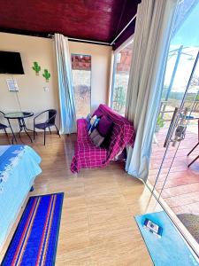 a living room with a pink couch and a table at Chalé Sun Happy in Serra de São Bento