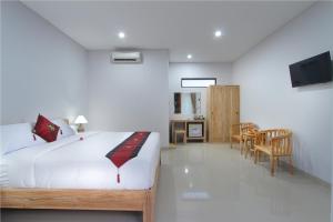 a bedroom with a bed and a table and chairs at Sleepwell Seminyak in Seminyak
