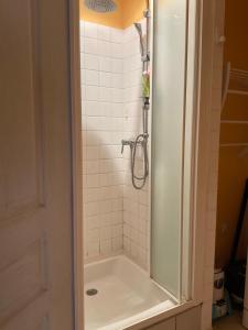 a bathroom with a shower with a white tiled wall at Grand T2 Côte de granit rose plages et commerces à proximité in Trégastel