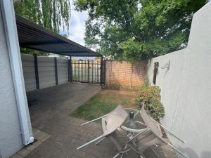 patio con 2 sedie e recinzione di Secure cottage with Wifi and PLEX OR Tambo Airport a Germiston