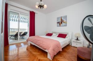 a white bedroom with a bed and a balcony at Apartments Duje in Dugi Rat
