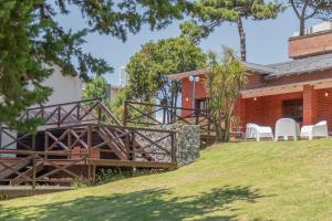 a house with a wooden bridge and chairs on a lawn at Tangerina Apart Hotel - Villa Gesell in Villa Gesell