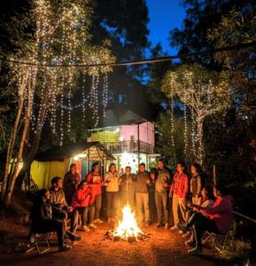 a group of people standing around a fire at Green porticos villa munnar #MUNNAR in Anachal