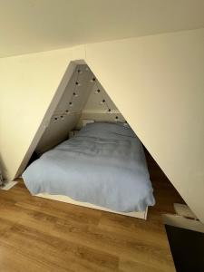 ein Schlafzimmer mit einem Bett in Dreiecksform in der Unterkunft Cute cottage house in the city centre with terrace in Den Haag