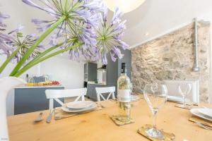 Una mesa de comedor con una botella de vino y flores moradas. en Ysgubor-Bennar, en Dyffryn