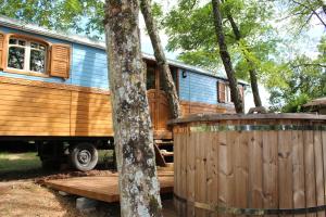 a blue and wooden caravan parked in the woods at Roulotte Zelena Hora in Cadalen