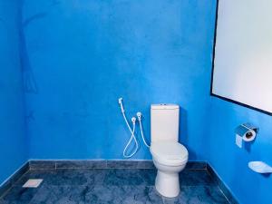 a blue bathroom with a toilet and a blue wall at Sigiri White Queen's Lodge in Sigiriya