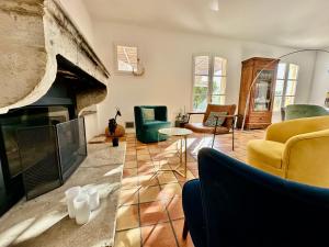 a living room with a fireplace and yellow chairs at Le Clos du Vialle in Grillon