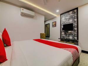 a hotel room with a bed and a tv at Capital O Pratibha Grand in Vijayawāda