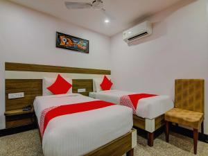 a hotel room with two beds and a chair at Capital O Pratibha Grand in Vijayawāda