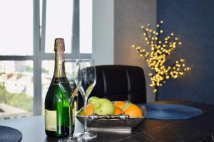 a bottle of wine and a bowl of fruit on a table at Дизайнерські апартаменти в ЖК DreamTown 10б in Luts'k