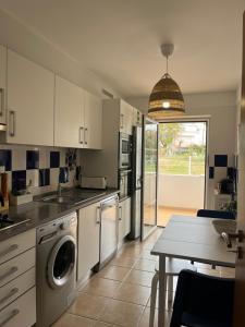 a kitchen with a washer and dryer and a table at Cabanas De Miramar in Tavira