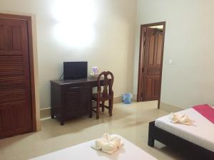 a bedroom with a desk and a bed and a television at IKI IKI Guesthouse in Siem Reap