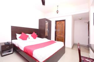 a bedroom with a large bed with red pillows at Hotel O Dwarika Inn in Jabalpur