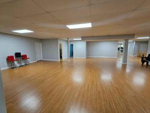 an empty room with a wooden floor and red chairs at White House Canada in Brampton