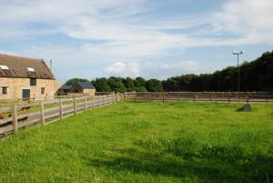a field with a wooden fence and a building at East Cawledge Farm in Alnwick