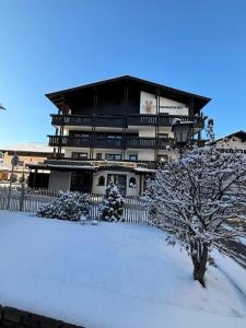 a building covered in snow with a tree in front of it at Hotel Mesnerwirt in Westendorf
