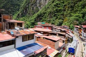 a train traveling through a town with a mountain at Rockrivers MachuPicchu in Machu Picchu