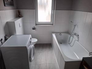 La salle de bains blanche est pourvue d'une baignoire, de toilettes et d'un lavabo. dans l'établissement Ferienwohnung 2, à Northeim 1 autre photo