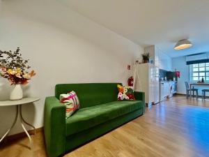 a green couch in a living room with a kitchen at Aquae Flaviae Urban Stay - Charm in Chaves