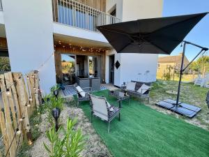 a patio with chairs and an umbrella on the grass at T3 Lumineux avec super Terrasse in Saint-Gilles-Croix-de-Vie