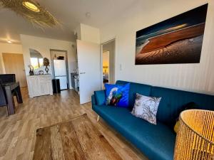 a living room with a blue couch and a kitchen at T3 Lumineux avec super Terrasse in Saint-Gilles-Croix-de-Vie