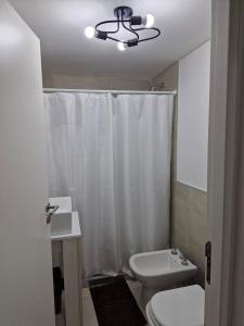 a bathroom with a white shower curtain and a toilet at Nuevo departamento in Neuquén