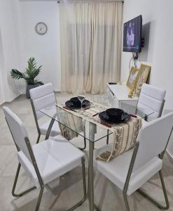 a dining room with a glass table and white chairs at Nuevo departamento in Neuquén