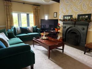 ein Wohnzimmer mit grünen Sofas und einem Kamin in der Unterkunft Grange Cottage in Belmont