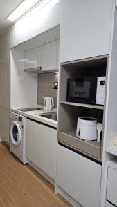 a white kitchen with a microwave and a washer and dryer at 헤세드 in Sŭngch'ŏn-ni