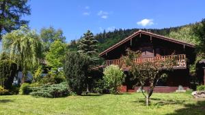 a log house with a balcony in a yard at Chalet du Grand Arbre in Le Ménil