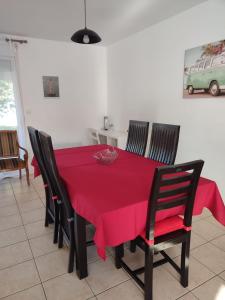 a dining room with a red table and chairs at Location 4-6 personnes in Grayan-et-lʼHôpital