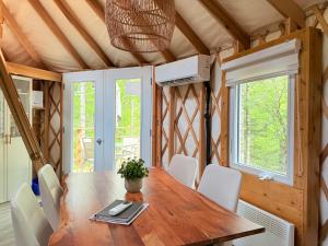 a dining room with a wooden table and white chairs at Exode en Nature in Sainte-Rose-du-Nord