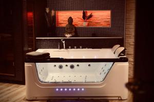 a bath tub in a bathroom with a picture on the wall at Pause Thermale Suite in Herstal