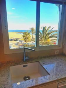 eine Küchenspüle mit Strandblick vom Fenster aus in der Unterkunft Encalma Vacacional siente disfruta vive la playa in Puerto de Sagunto