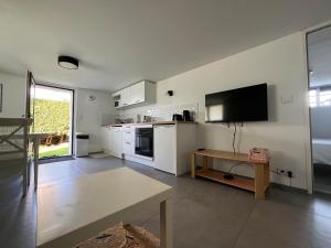 eine Küche mit weißen Schränken und einem Flachbildfernseher in der Unterkunft Appartement Vannes avec jardin in Saint-Avé