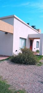 une maison blanche avec une brousse devant elle dans l'établissement Las Golondrinas, à Veinticinco de Mayo