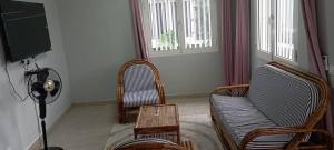 a living room with chairs and a tv and a table at Océan Voyages Mitsamihouli in Mitsamiouli