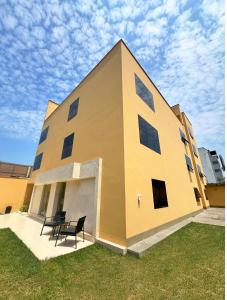 a yellow building with two black chairs in front of it at Rig Vêda Hotel in Lima