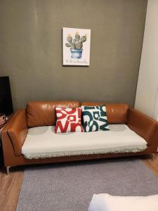 a brown leather couch with pillows in a living room at gd house! in Hyoja-dong